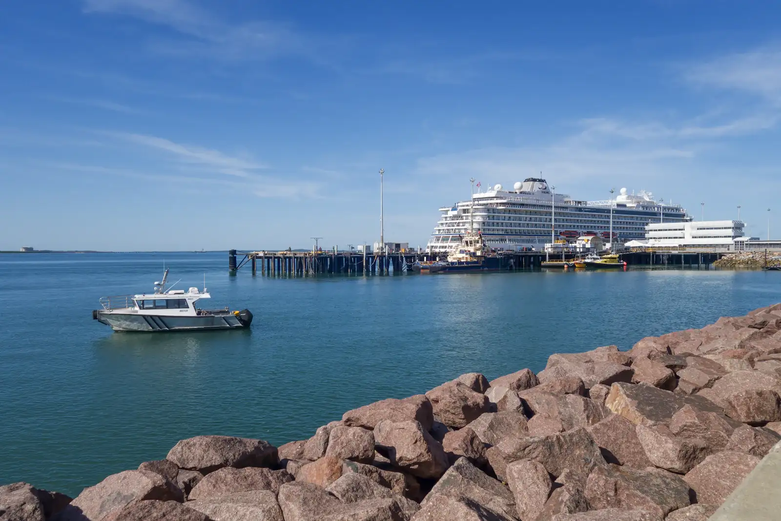 A boat on Darwin Harbour, with a cruise ship at the wharf